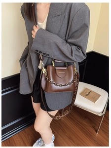 Close-up of brown PU leather bucket bag featuring a gold chain and geometric print strap