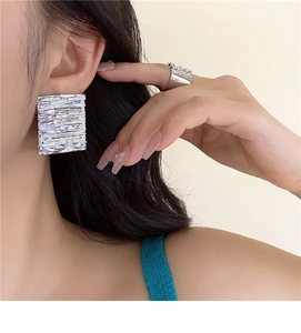 Detail of silver square earrings with textured metallic pleats and brushed finish