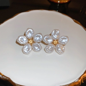 Orecchini a fiore in perla stile francese con stami dorati su un piatto di ceramica bianca