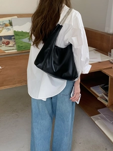 Close-up of a black leather tote bag with silver chain strap shown in a studio