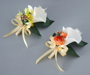 Detail of white calla lily wedding corsages with silk bows and pearl accents on grey background