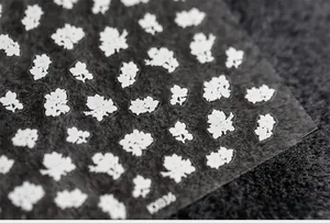 Macro detail of 5D floral nail stickers with white flower patterns on model KK036