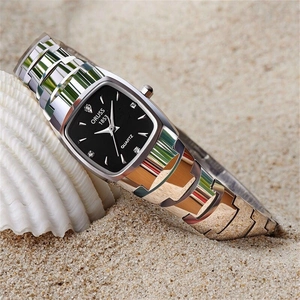 Detailed view of silver tonneau quartz watch with black dial on beach sand and shells