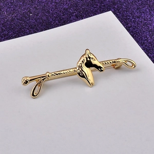 Macro shot of gold horse head brooch with textured rope bar and secure pin back clasp