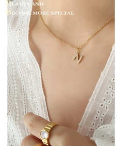 Detailed view of gold plated necklace with zircon paved letter N pendant on model