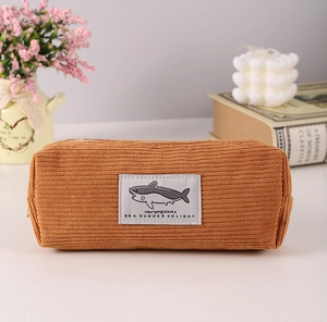 Close-up of brown corduroy pencil case with shark patch and sea summer holiday label