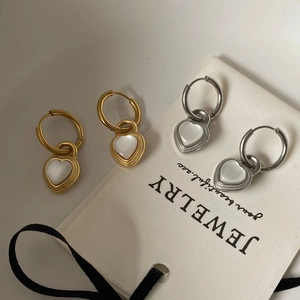 Detail of heart pendants in gold and silver finish with white cat-eye stone inlay