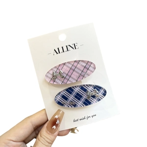 Pink and blue plaid hair clips with silver bow accents on a display card