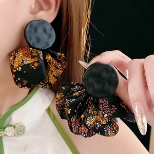 Close-up of vintage irregular floral earrings with black round studs and orange fabric petals