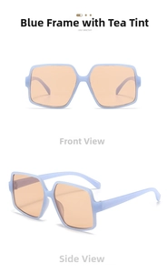 Detail view of oversized square sunglasses with light blue frames and amber lenses