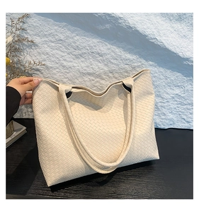 Close-up of the woven leather texture and large capacity design of the cream tote bag