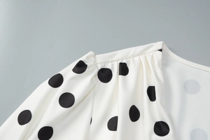 Dettaglio dell'abito bianco a pois con maniche a sbuffo e cuciture sulle spalle a V
