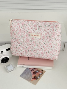 Detail of pink floral corduroy cosmetic bag with diamond quilting and brand label