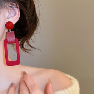 Close-up of model wearing red flocked leather rectangular drop earrings with silver needle