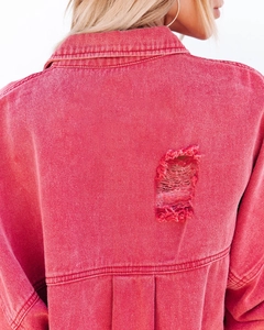 Close-up of distressed ripped details and raw hem on red denim jacket back