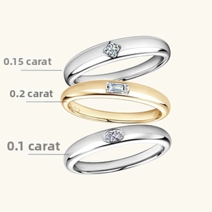 Close-up of three stacked moissanite rings in round, baguette, and oval cuts on beige