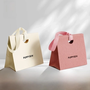 Detail of minimalist gift paper bags with wide ribbon handles and circular cut-outs