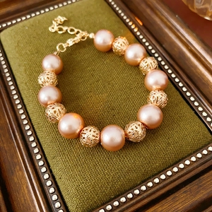 Detail of pink pearl bracelet with hollow gold beads on a vintage green velvet pad