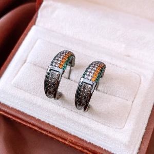 Macro detail of vintage C-shaped earrings with colorful zircons on black gold plating