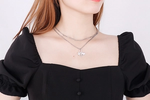 Close-up of a double-layered silver butterfly pendant necklace worn by a fashion model
