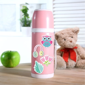 Close-up of cute cartoon stickers on a pink kids insulated bottle on a wooden table