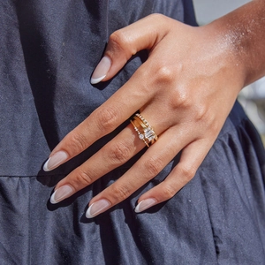 Close-up of three-piece stacked gold stainless steel rings with square zircon stones