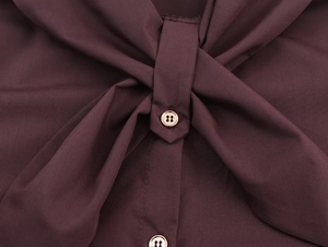 Detail showing the knotted tie design and golden buttons on this maroon long sleeve top