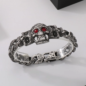 Detail of vintage 304 stainless steel skull bracelet with red ruby eyes and floral links