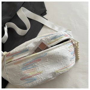 Detail of white jacquard chest bag with colorful wave embroidery and cosmetics inside