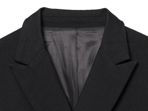 Detailed close-up of a black blazer featuring sharp lapel tailoring and premium fabric