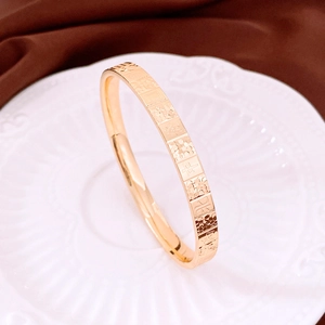 Detail view of a gold-plated bangle with traditional Chinese character engraving on silk