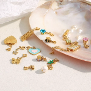 Detail of 18K gold-plated stainless steel charms with shell and pearl on white background
