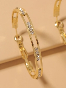 Detail of double-layer gold hoop earrings with sparkling rhinestones and metallic texture