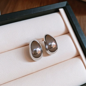 Macro shot of silver teardrop stud earrings with a high-polished mirror finish in a box