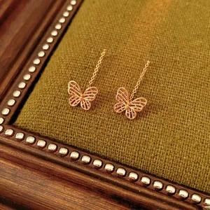Vintage gold butterfly chain earrings with intricate hollow wings on green velvet