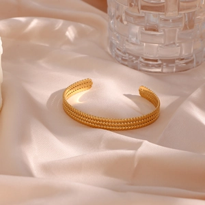 Macro shot of gold-plated twisted cable texture on adjustable stainless steel bangle