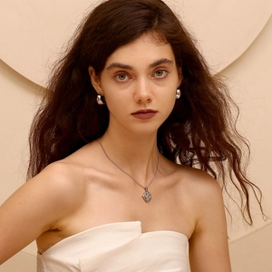 Dettaglio di collana a cuore in argento e orecchini a cerchio indossati da una modella