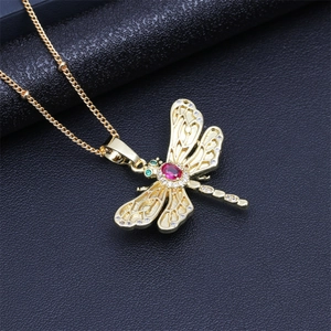 Macro view of gold dragonfly pendant with colorful crystals on black leather