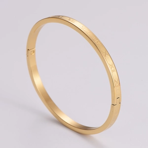 Macro shot of gold-plated bangle showing etched Roman numerals and secure hinge clasp