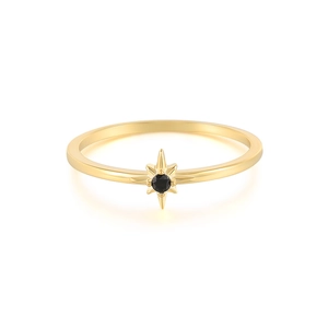 Macro shot of gold ring with black round gemstone in a celestial starburst setting