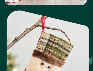 Detail of burlap Santa Claus Christmas stocking hanging on a wooden branch with warm lights