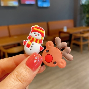 Detail of Christmas snowman and reindeer hair clips held by hand in a cozy cafe setting