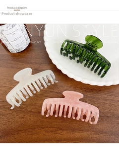 Deep green, cream, and pink marble acetate hair claws displayed on a wooden surface