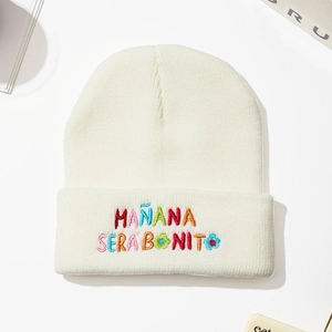 Close-up of white knitted beanie featuring colorful MAÑANA SERA BONITO embroidery detail