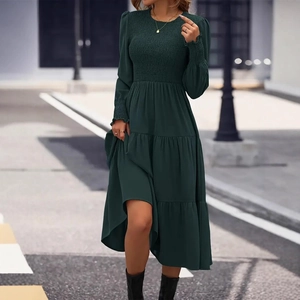 Detailed close-up of dark green tiered dress with smocked elastic cuffs and round neck