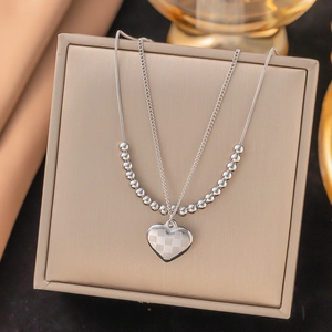 Detail of silver double-layered heart necklace with checkerboard pattern on jewelry box