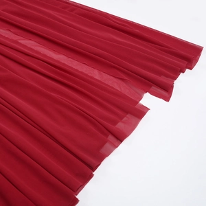 Détail du tissu en tulle rouge multicouche sur une robe ajustée aux plis translucides