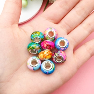 Macro shot of colorful ink-painted resin beads with metal core in a hand