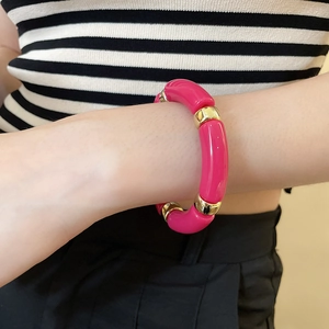 Detail of pink acrylic beaded bracelet with gold spacers worn on a model's wrist