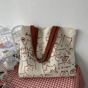Detail of artistic canvas tote bag showing durable brown straps on a checkered tablecloth